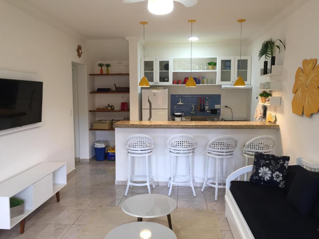 uma sala de estar com uma cozinha e um bar com bancos em Flat Amarilis apto inteiro em Riviera de São Lourenço