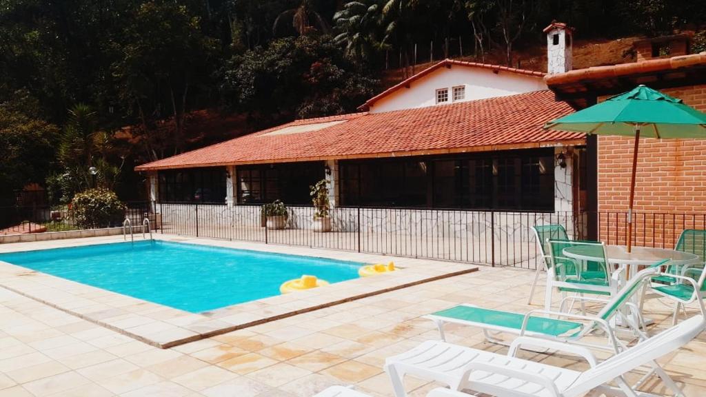 uma piscina com cadeiras, uma mesa e um guarda-sol em Pousada Pé da Tartaruga em Teresópolis