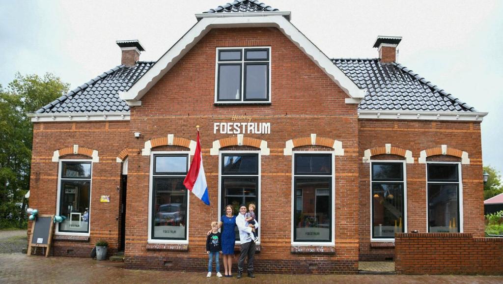 un grupo de personas de pie en frente de un edificio en B&B Herberg Foestrum, en Westergeest