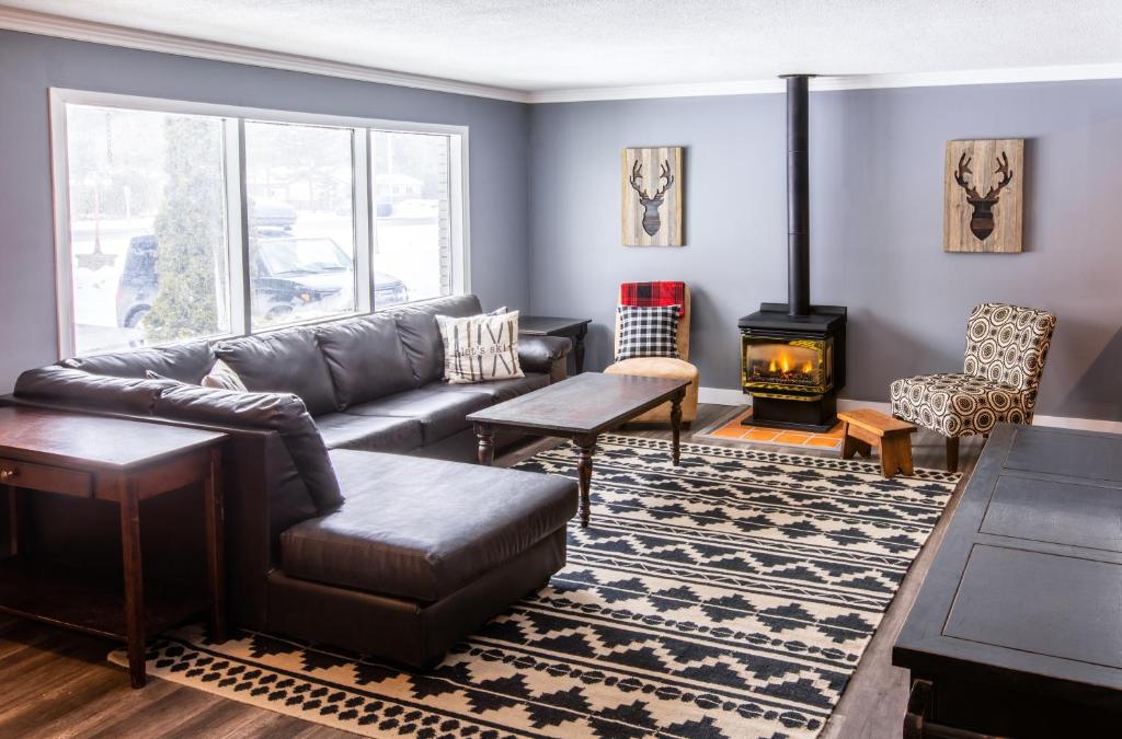 a living room with a leather couch and a fireplace at 4 Bedroom Rustic Chalet in Blue Mountains