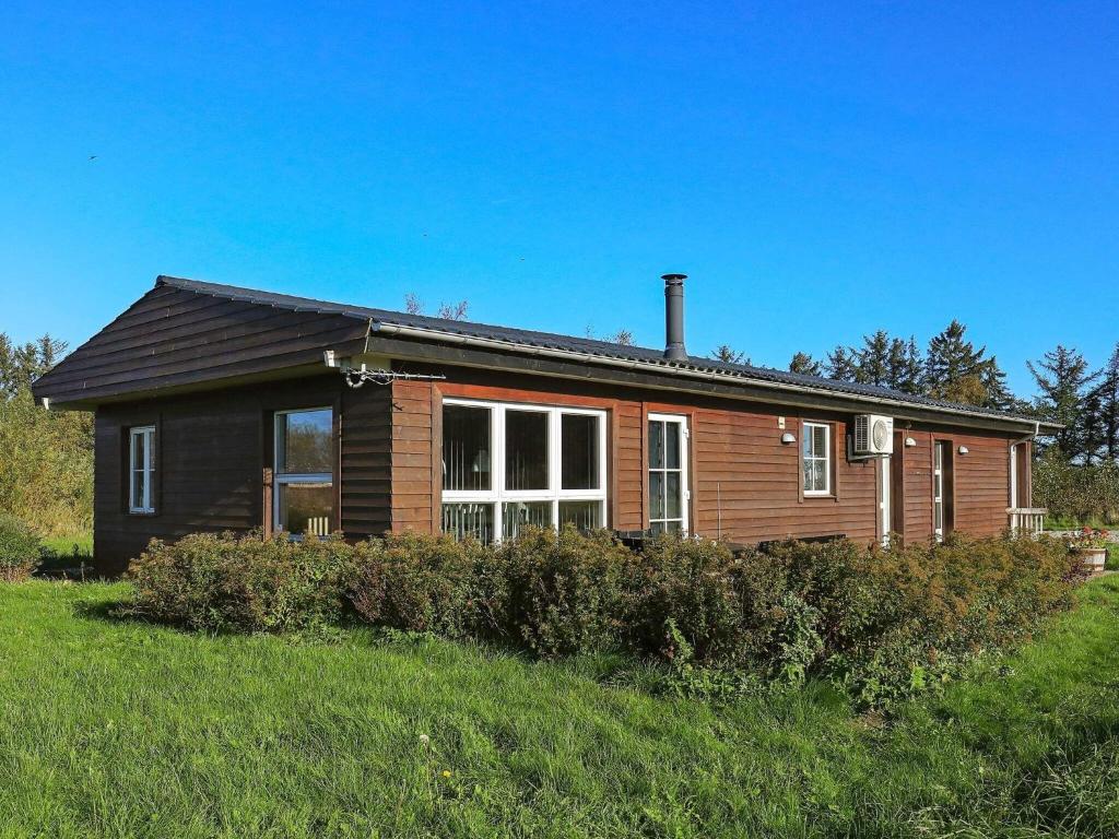 a wooden house with a large window in a field at 6 person holiday home in Fjerritslev in Fjerritslev