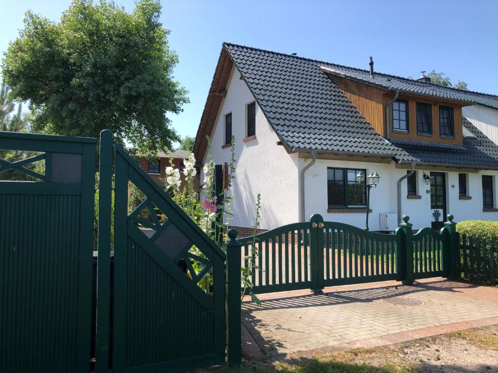 uma cerca verde em frente a uma casa branca em Haus Hugo Zingst em Zingst