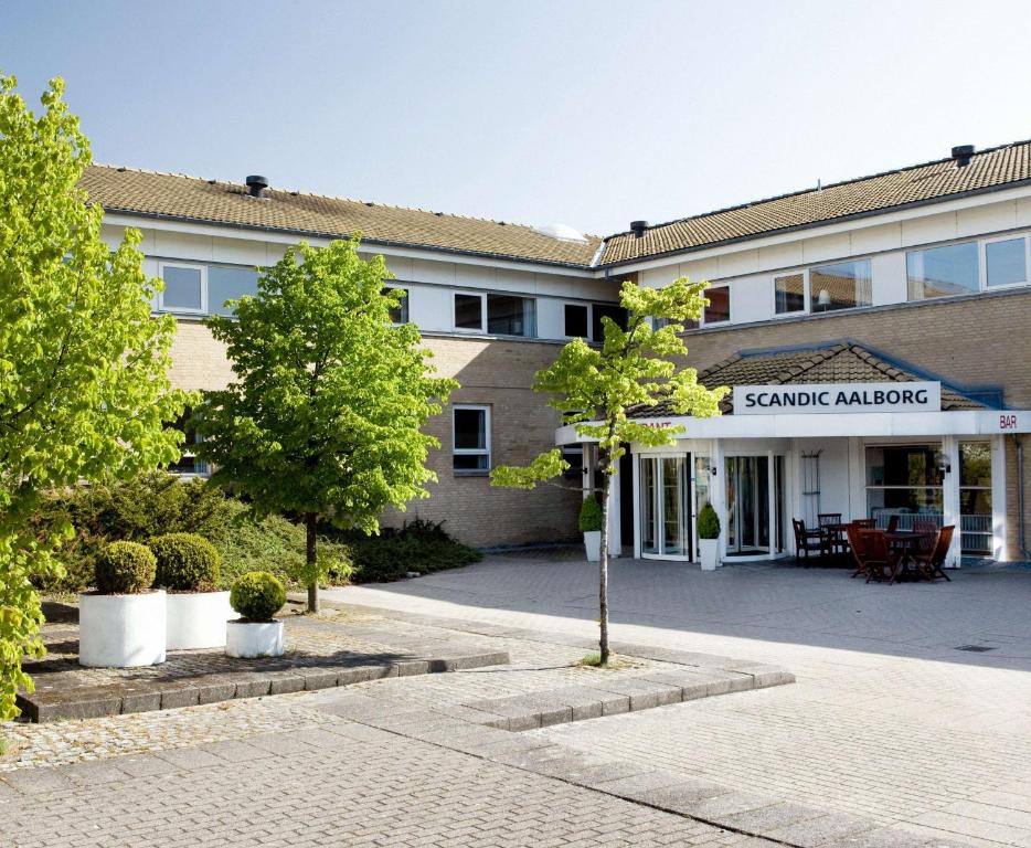 a building with a courtyard with trees in front of it at Scandic Aalborg Øst in Aalborg