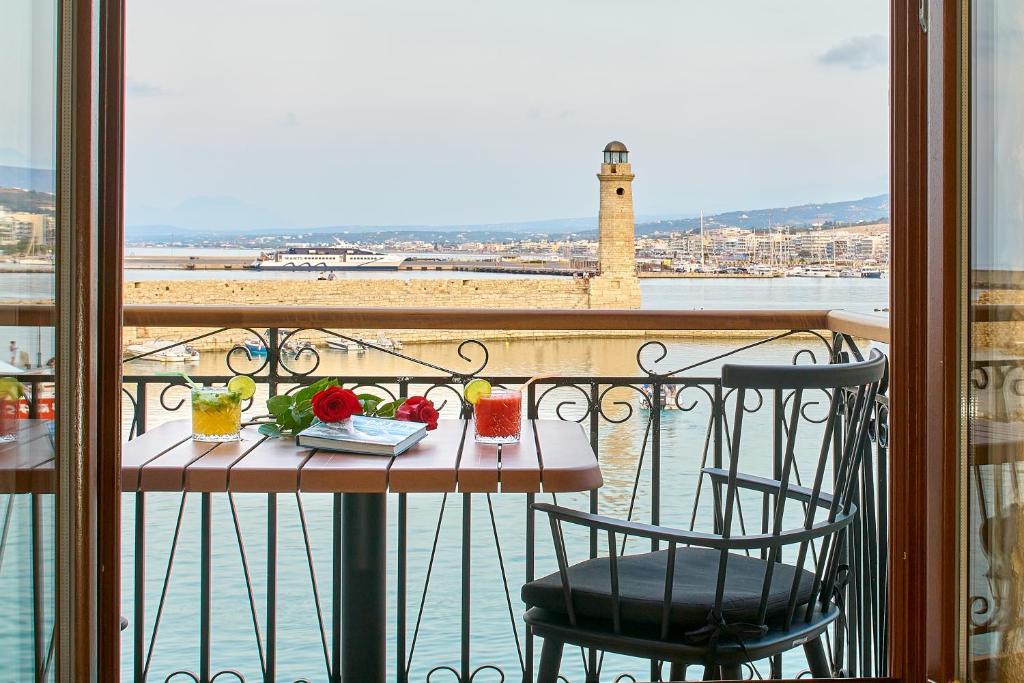 Vista Del Porto Luxury Suites في مدينة ريثيمنو: طاولة وكراسي على شرفة مطلة على الماء