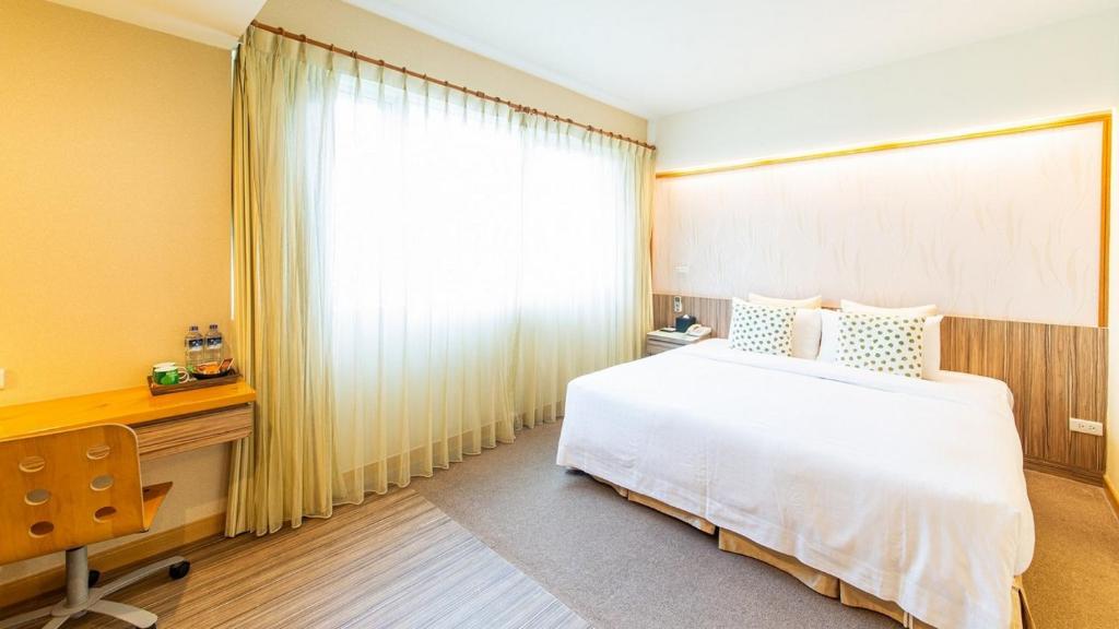 a bedroom with a white bed and a desk and a window at Hotel Color in Taipei