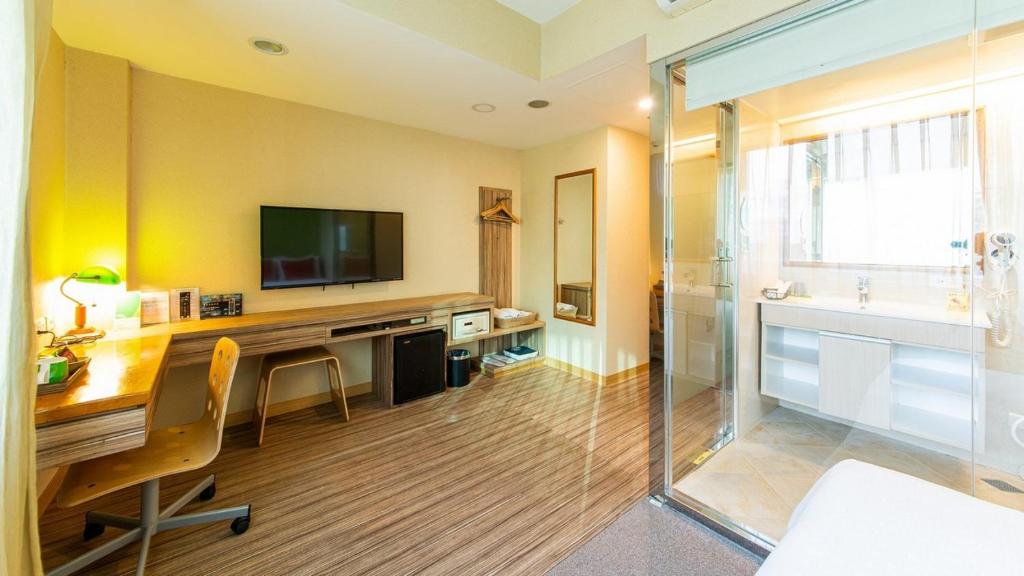 a room with a desk with a television and a shower at Hotel Color in Taipei