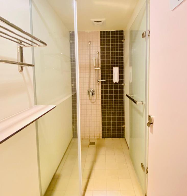a bathroom with a shower with a glass door at Hey Bear Capsule Hotel in Taipei