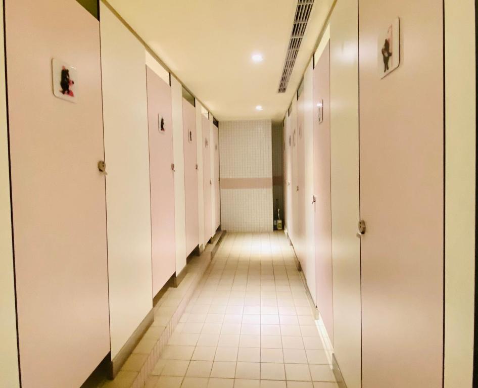 a long corridor with white doors and a tile floor at Hey Bear Capsule Hotel in Taipei