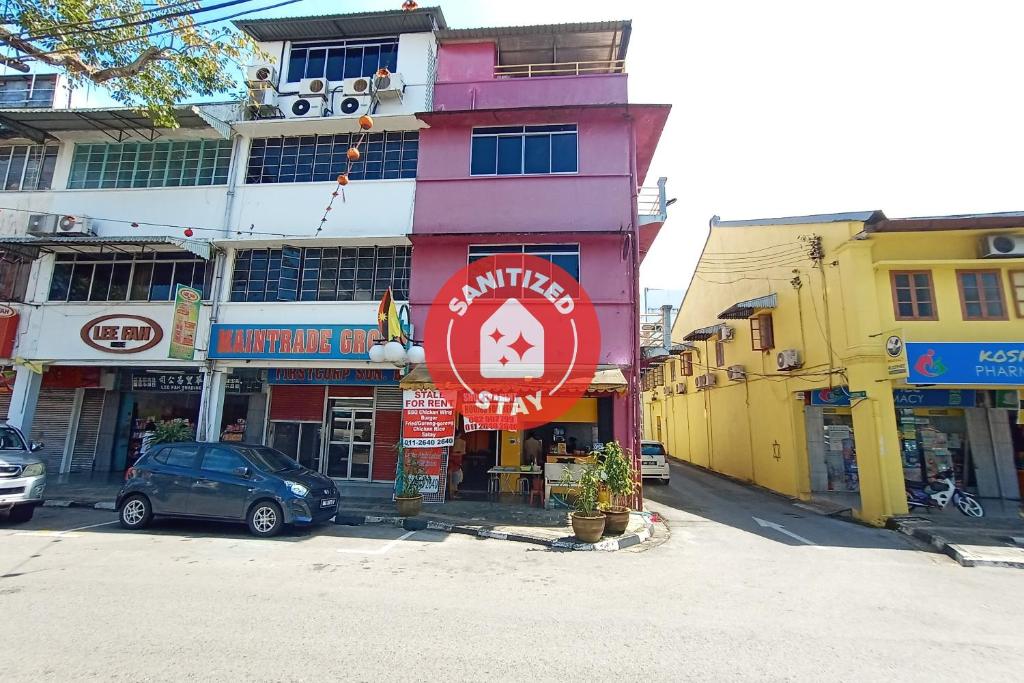 een roze gebouw met een bord op een straat bij SPOT ON 90119 Bed's Guesthouse in Kuching