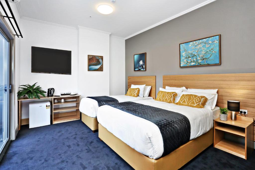 a hotel room with a large bed and a television at Meridian Hotel Hurstville in Sydney