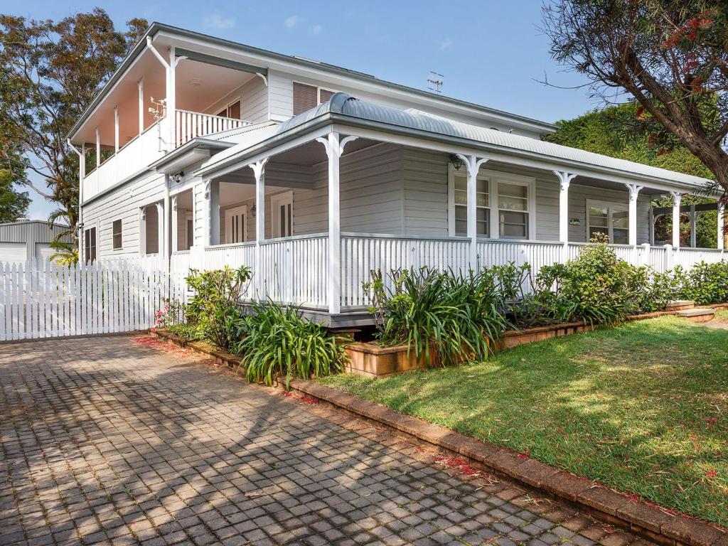a white house with a white fence and a yard at Patch of Paradise Iluka in Tea Gardens