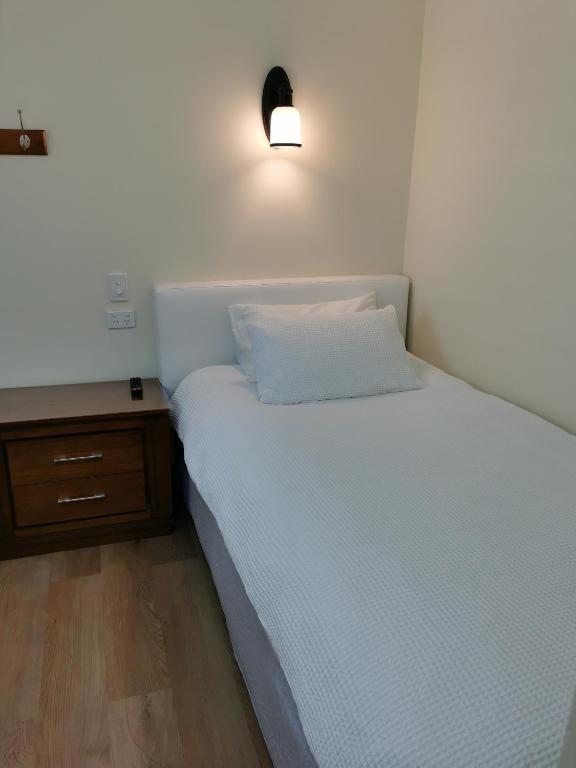 1 dormitorio con cama blanca y mesita de noche en BHA unit 5 en Perth