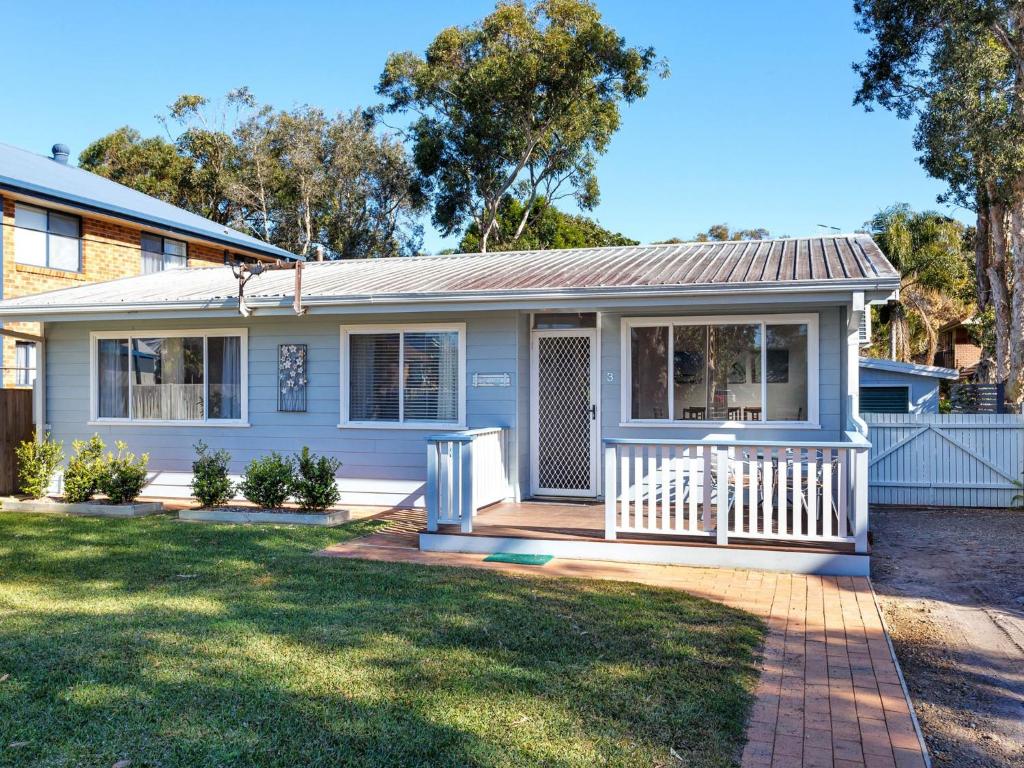 una casa bianca con portico e cortile di Surfs Up a Hawks Nest