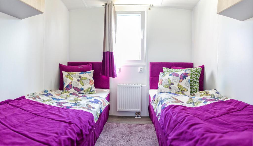- 2 lits dans une chambre avec des draps violets dans l'établissement Domek Apartamentowy, à Darłówko