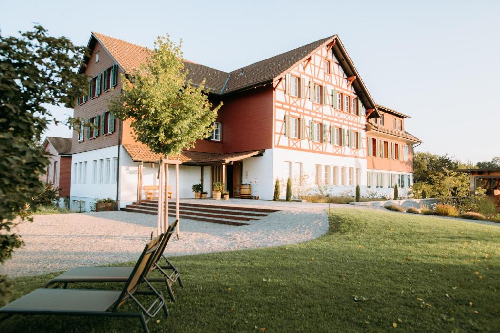 a building with a tree and chairs in front of it at Gasthof Sunnebad in Sternenberg