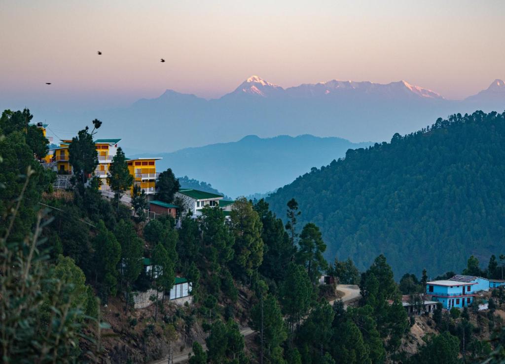 a village on a hill with mountains in the background at juSTa Mukteshwar Retreat & Spa in Mukteswar