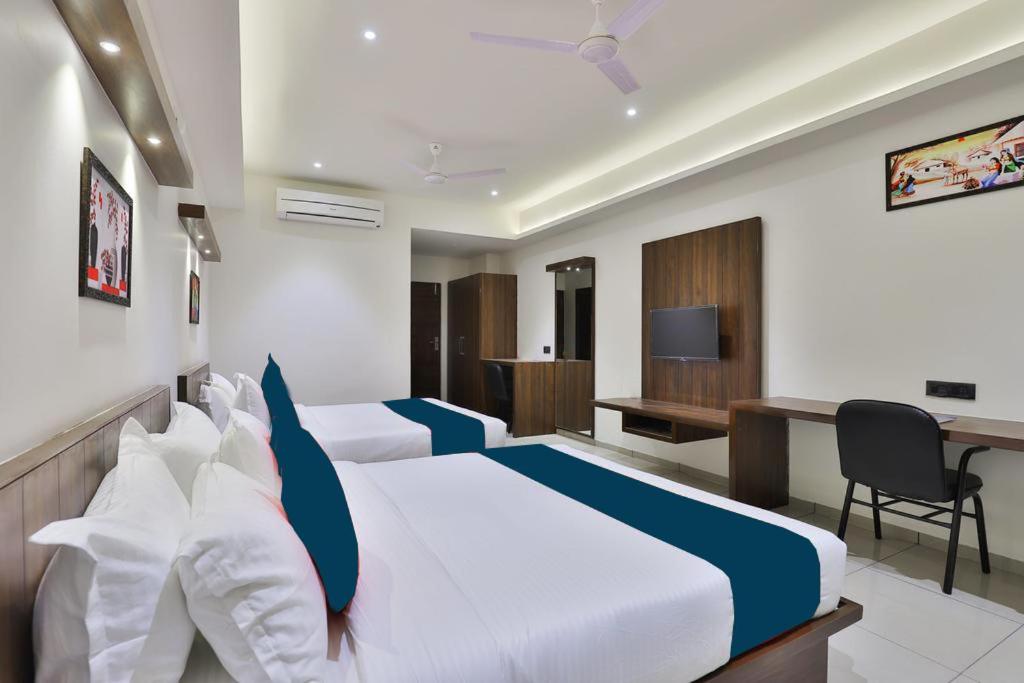 a hotel room with two beds and a desk at Hotel Sparsh Inn - Chandkheda in Ahmedabad