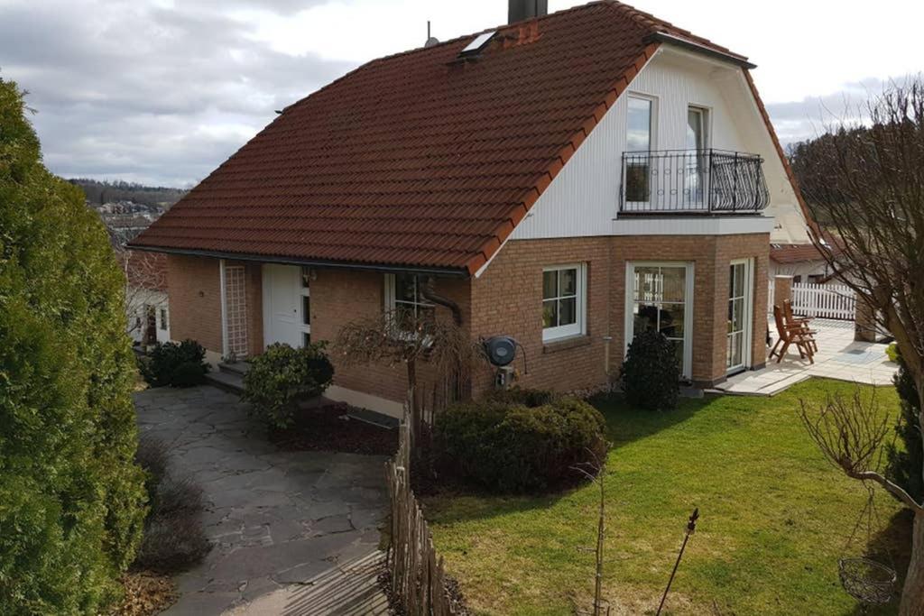 une maison avec un toit rouge et un balcon dans l'établissement Idyllische Ferienwohnung zum Wohlfühlen+Entspannen, à Lichtenstein