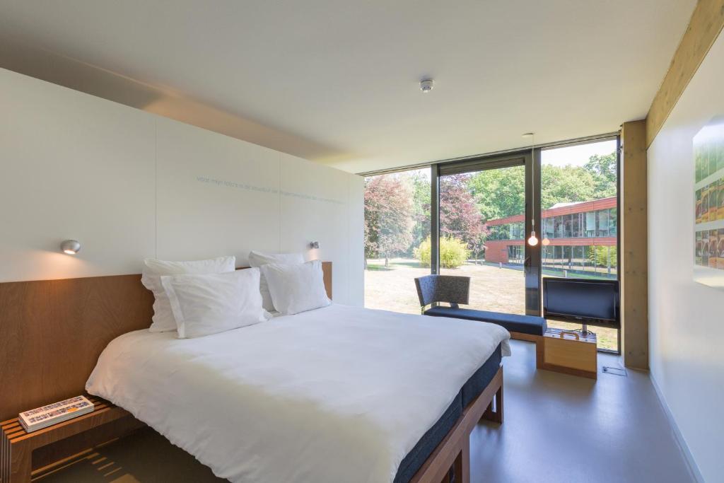 een slaapkamer met een groot bed en een groot raam bij Landgoed de Horst in Driebergen