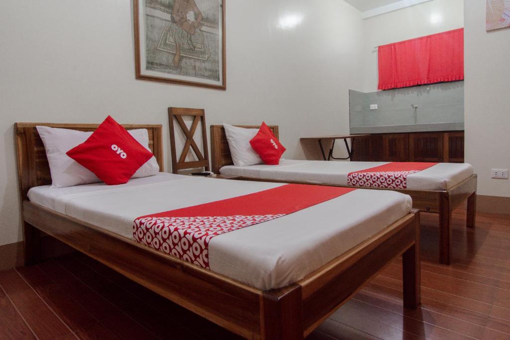 two beds with red pillows in a room at OYO 658 Roccksar Pension in Puerto Princesa City