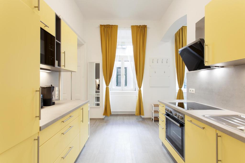 kuchnia z żółtymi szafkami i dużym oknem w obiekcie GAL Apartments Vienna w Wiedniu