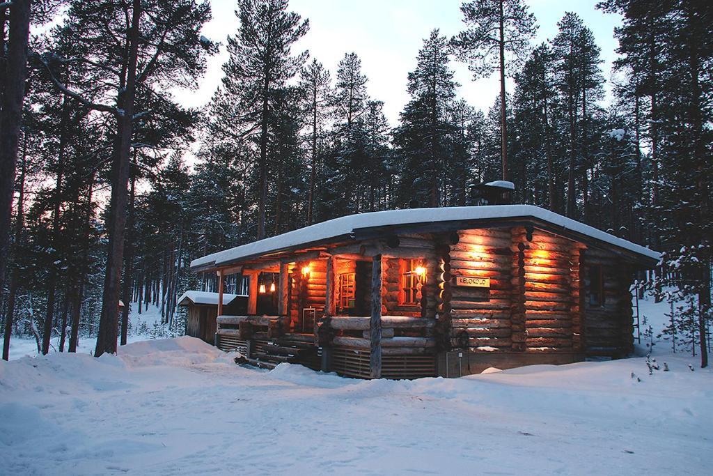 une cabane en rondins dans la neige éclairée dans l'établissement Kelokolo, Ivalo, à Ivalo