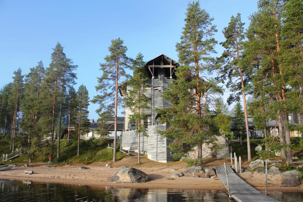 a house on a hill next to a body of water at Hotel Kalevala in Kuhmo