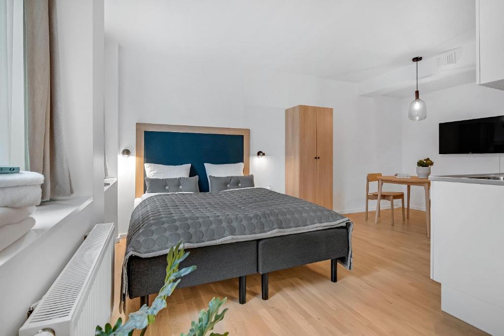 a bedroom with a bed and a kitchen with a table at STUDIO1A Hotel Apartments in Copenhagen