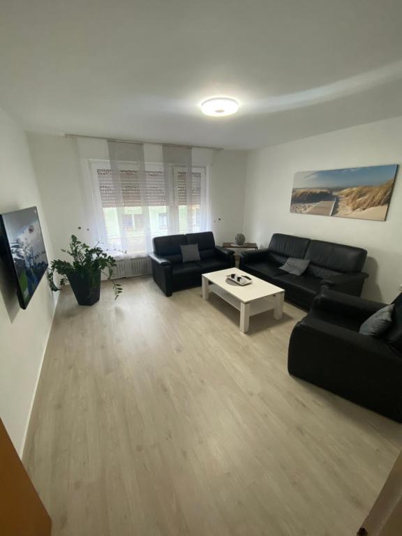 Sala de estar con sofás negros y mesa de centro en Apartment Lori en Mönchengladbach