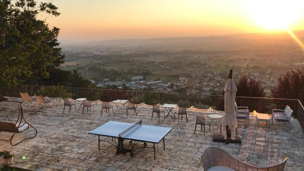 a patio with tables and chairs and an umbrella at Villa Clara in Assisi