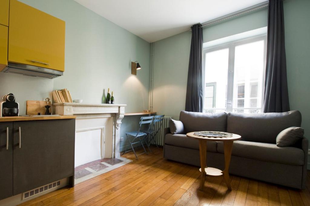 a living room with a couch and a table at Suites & Hôtel Helzear Montparnasse in Paris