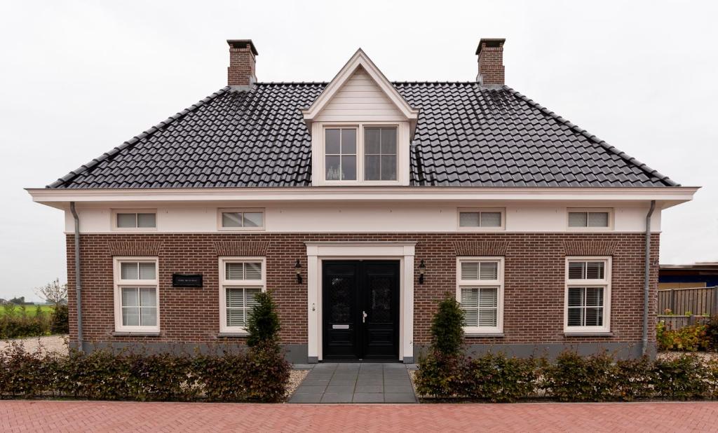une maison en briques rouges avec un toit noir dans l'établissement Dinie's Bed en Brood, à 's-Heerenbroek