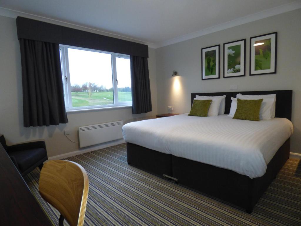 ein Hotelzimmer mit einem großen Bett und einem Fenster in der Unterkunft Greetham Valley in Greetham