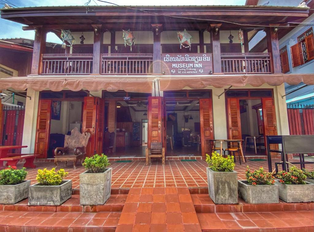 um edifício com vasos de plantas à sua frente em Luang Prabang Museum Inn & Travel em Luang Prabang