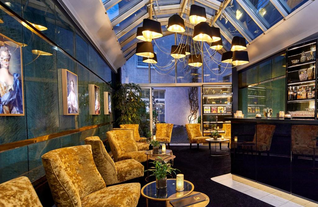 a bar with couches and chairs in a room at Das Carls Hotel in Düsseldorf