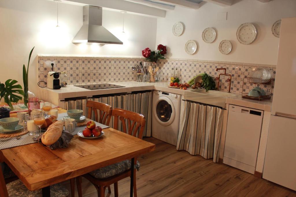 uma cozinha com uma mesa de madeira e uma cozinha com uma máquina de lavar roupa em Ca la Casilda em Prades