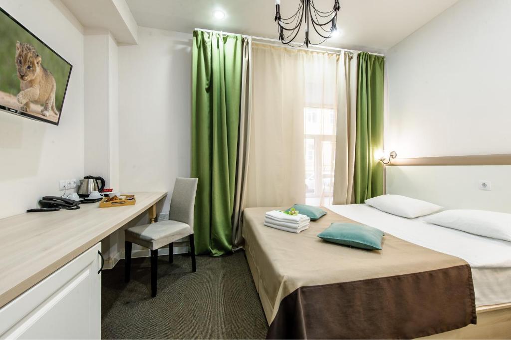 a room with two beds and a desk and green curtains at Epigraph Hotel in Saint Petersburg