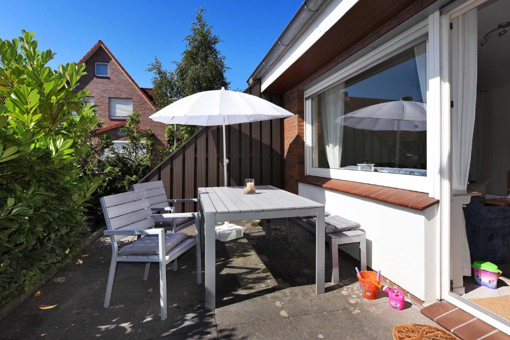 a table and chairs with an umbrella on a patio at Ferienwohnung Bensersiel Ahoi in Bensersiel