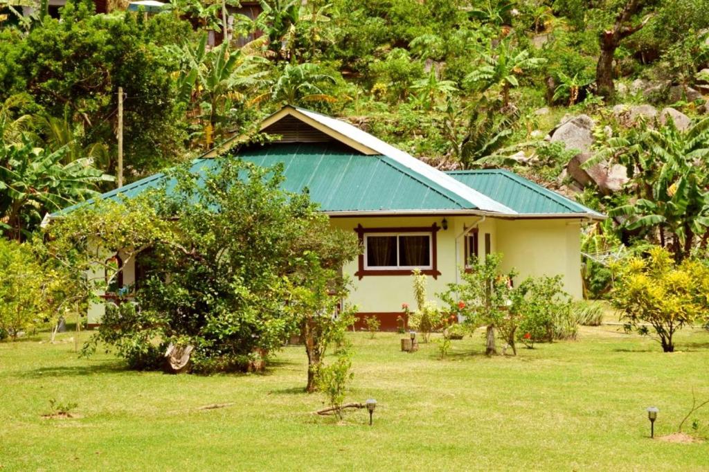 a small house with a blue roof in a field at Dan Zoranz Self Catering Guest House in La Digue