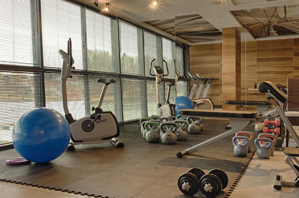 a gym with exercise equipment in a room with windows at Hotel Mikołajki Leisure &amp; SPA in Mikołajki