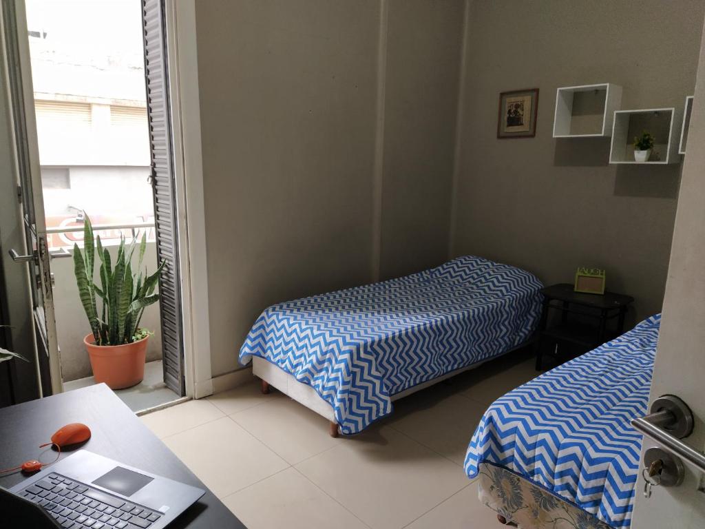 a room with two beds and a desk with a laptop at HA! 1 Resi para estudiantes in Cordoba