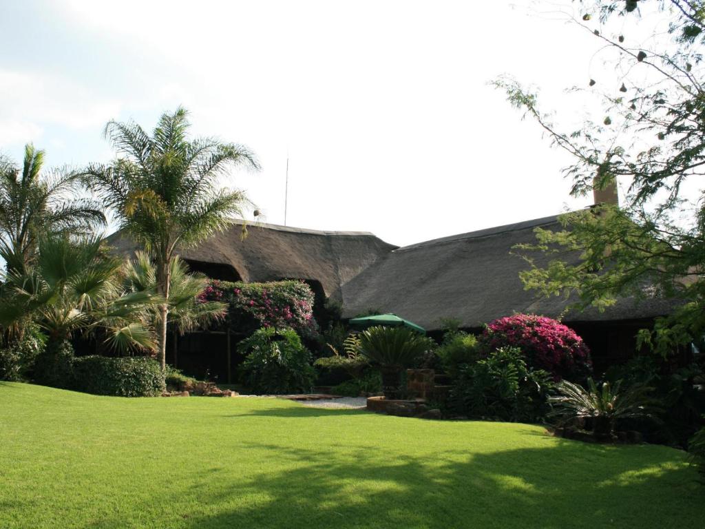 a house with a yard with green grass and trees at Glen Afric Country Lodge in Hartbeespoort