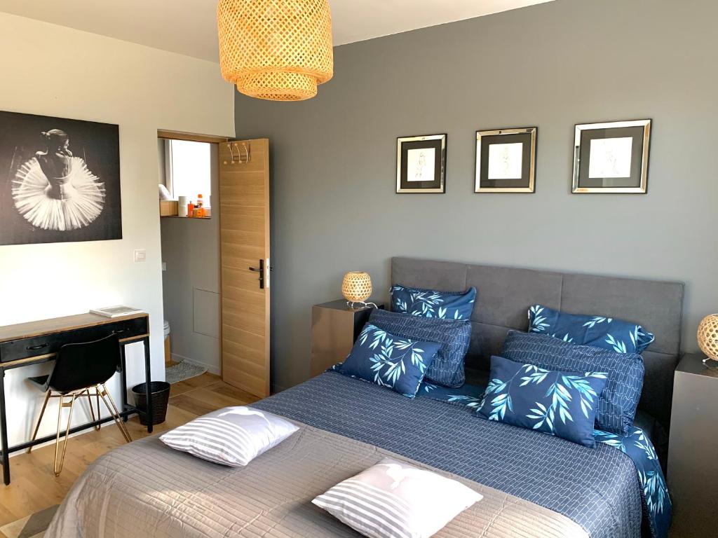 een slaapkamer met een bed met blauwe kussens en een bureau bij La Demeure Marcquoise in Marcq-en-Baroeul