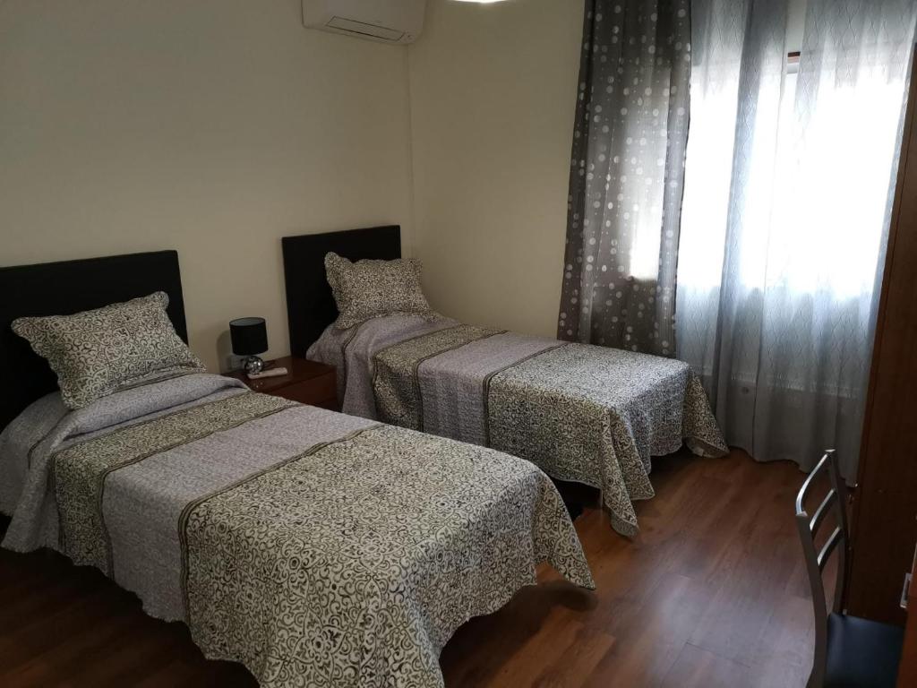Apartamento Mondego في بيناكوفا: غرفة نوم بسريرين ونافذة
