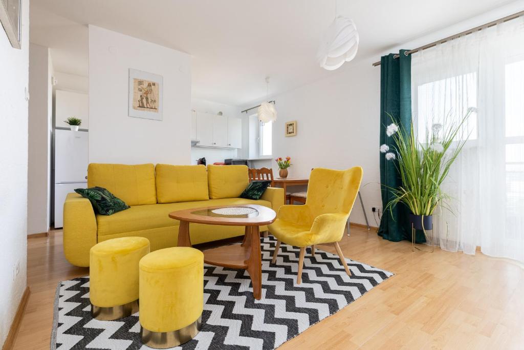 a living room with a yellow couch and yellow chairs at ap4you Tauron Cracow in Kraków