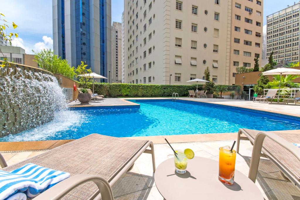 a swimming pool with a table and drinks on a patio at Transamerica Prime International Plaza (Paulista) in São Paulo