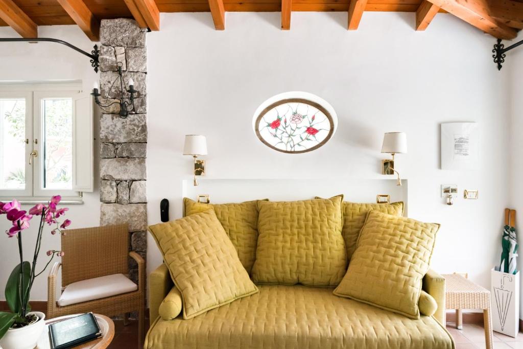 ein gelbes Sofa im Wohnzimmer mit einer Uhr an der Wand in der Unterkunft VILLA SCHULER GARDEN SUITE TAORMINA IN SELF CATERING in Taormina