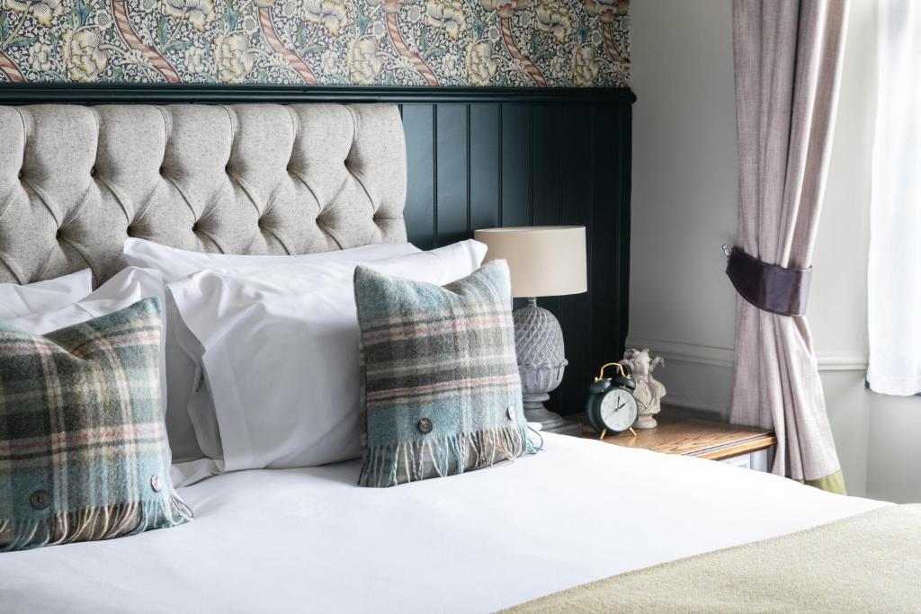 1 dormitorio con 1 cama blanca con cabecero y almohadas en The Fleece at Cirencester en Cirencester