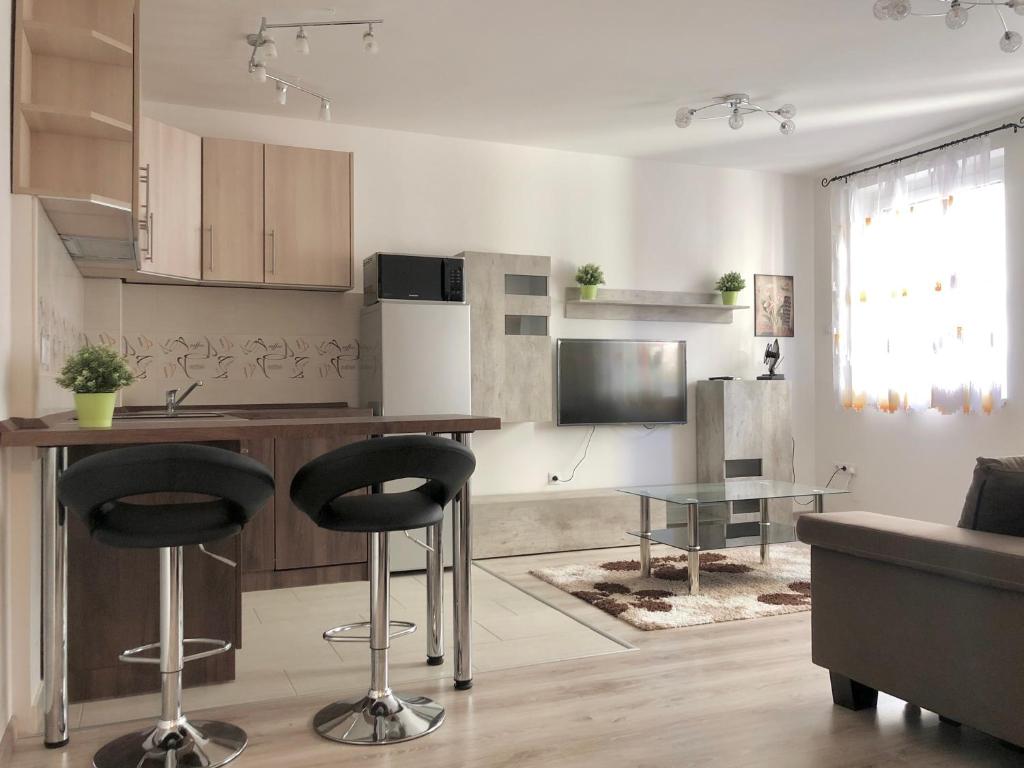 une cuisine avec une table et deux tabourets de bar dans l'établissement Exclusive Home - D. apartman, à Pécs