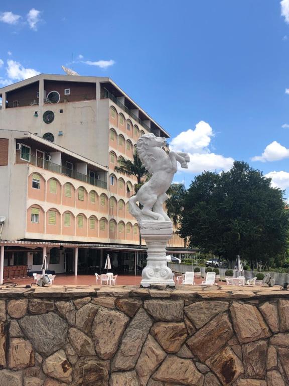 a statue in front of a large building at Hotel Cavalinho Branco - Apartamento 516 in Águas de Lindoia